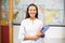 Portrait of smiling school teacher holding books in classroom