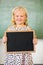 Portrait of smiling schoolgirl holding slate in classroom