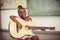 Portrait of smiling schoolgirl playing guitar in classroom