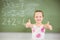 Portrait of smiling schoolgirl showing thumbs up in classroom