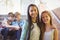 Portrait of smiling schoolgirls standing with arm around in corridor