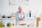 portrait of smiling senior with arms crossed standing at counter with fresh vegetables