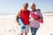 Portrait of smiling senior biracial couple holding yoga mats at beach on sunny day