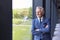 Portrait Of Smiling Senior Businessman CEO Chairman Standing By Window Inside Modern Office Building