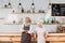 portrait of smiling senior coffee shop owners in aprons standing at counter