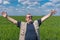 Portrait of smiling senior farmer standing inside unripe crops field