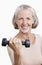 Portrait of smiling senior woman with dumbbell against white background