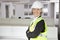 Portrait of smiling senior woman in reflector vest and hard hat at office