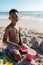 Portrait of smiling shirtless african american boy playing with sand pail and shovel at beach