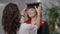 Portrait of smiling slim beautiful young woman looking at mother putting on graduation hat. Happy smart Caucasian