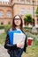 Portrait of smiling student with folders and cup of coffee outdoors on University background