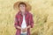 Portrait of smiling teenage farm boy is with oat seeds in cupped palms at ripe field