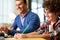 Portrait of smiling teenaged latin boy in glasses making notes while sitting at the desk together with his father and