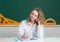 Portrait of smiling teenager girl over blackboard, friendly laughing. Cute college female student in hight school.