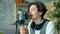 Portrait of smiling teenager speaking in mic in sound recording studio alone