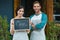 Portrait of smiling waiter and waitress standing with chalkboard