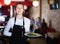 Portrait of smiling waitress with serving tray meeting restaurant guests