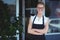 Portrait of smiling waitress standing with arms crossed