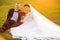Portrait of smiling wedding couple sitting on grassy field