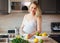 Portrait of smiling white Caucasian blonde pregnant woman cutting citrus lime lemon making juice standing in kitchen