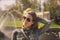 Portrait of a smiling woman in aviator glasses against the background of a fountain in gold tones