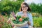 Portrait of smiling woman with basket of different fresh vegetables and herbs
