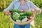 Portrait of smiling woman with basket of different fresh vegetables and herbs