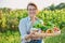 Portrait of smiling woman with basket of different fresh vegetables and herbs