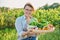 Portrait of smiling woman with basket of different fresh vegetables and herbs