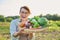 Portrait of smiling woman with basket of different fresh vegetables and herbs