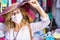 Portrait of a smiling woman blonde and curly haired enjoying  the flea market with a beautiful handicraft multi colored hat,