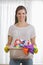 Portrait of smiling woman carrying basket of cleaning supplies at home