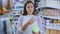 Portrait of smiling woman consumer choosing product at beauty shop, using smartphone for scanning barcode