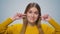 Portrait of smiling woman covers her ears with fingers at camera in studio.