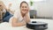 Portrait of smiling woman looking at her new robot vacuum cleaner working in living room. Concept of hygiene, household