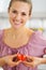 Portrait of smiling woman making heart with strawberry slices