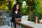 Portrait Of Smiling Woman Typing On Notebook While Working Online Using Laptop Computer. Female Sitting On Terrace