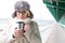 Portrait of smiling woman in warm clothing holding insulated drink container