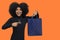 Portrait of a smiling young afro girl points to a shopping bag, concept of promotion, sales,