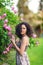 Portrait of a smiling young brunette Caucasian beautiful woman near rose bush, vertical, waist up