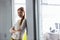 Portrait of smiling young businesswoman with arms crossed in doorway of office