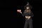 Portrait of smiling young girl in black clothes in pointed witchs hat with gift in hands. Isolation on black background. Halloween