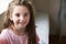 Portrait Of Smiling Young Girl Sitting On Window Seat At Home