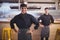 Portrait of smiling young wait staff standing with hands on hip against counter