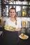 Portrait of smiling young waitress holding fresh Greek salad plate