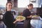 Portrait of smiling young waitress holding fresh salad against waiter at commercial kitchen