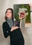 Portrait of a smiling young woman holding a photo of an ostrich with its mouth wide open