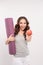 Portrait of smiling young woman holding rolled up exercise yoga