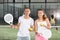 Portrait of smiling young woman and male posing on padel court