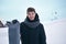 Portrait of snowboarder. Handsome man in ski suit is holding a snowboard, looking at camera and smiling. Man in the mountains